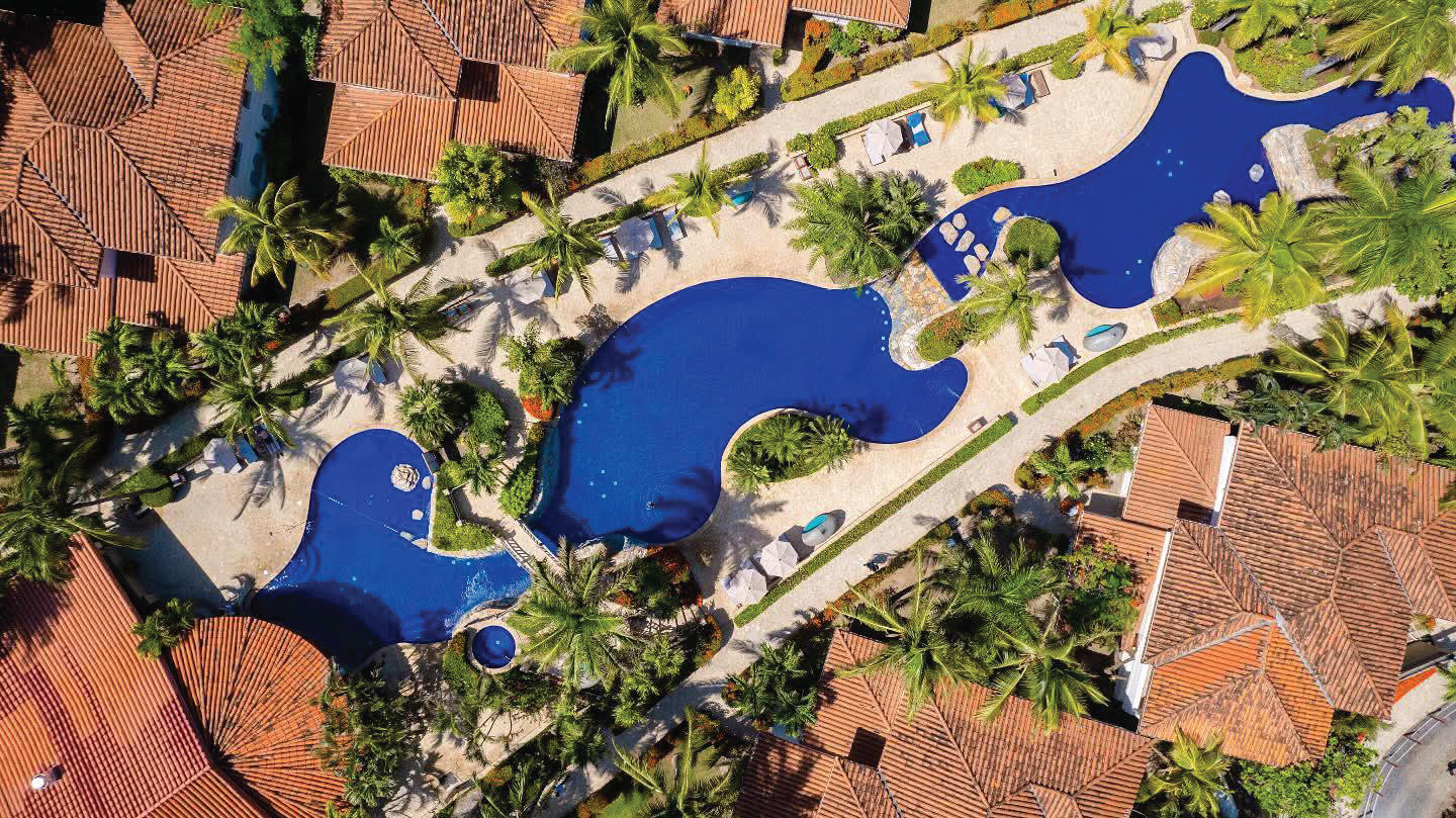 Aerial view of the Mayan Princess Beach & Dive Resort pools and palm-lined grounds in Roatán, Honduras